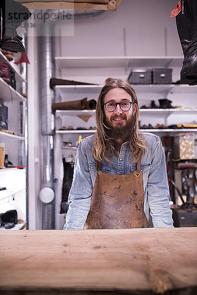 Porträt eines lächelnden Schuhmachers  der in der Werkstatt steht