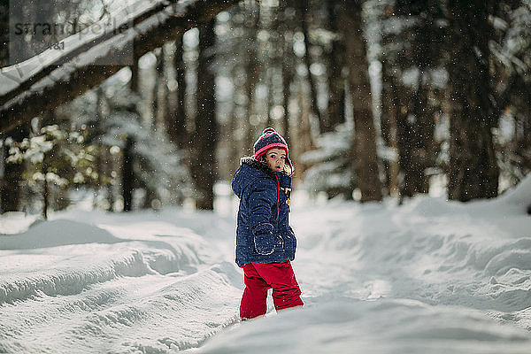 Porträt eines Mädchens auf schneebedecktem Feld im Wald stehend