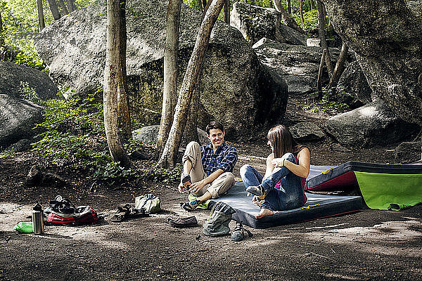Glückliches Paar entspannt sich auf Feld gegen Felsen im Wald