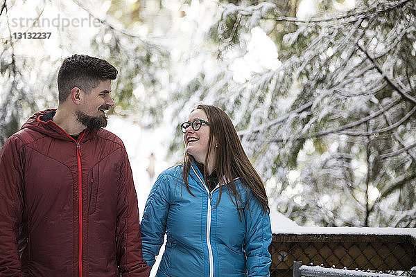 Lächelndes Paar  das sich im Winter im Wald im Lynn Canyon Park von Angesicht zu Angesicht gegenübersteht