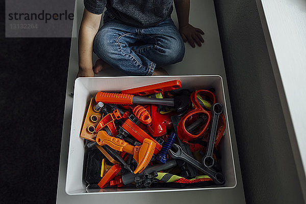 Niederer Teil eines Jungen mit Tischlerei-Spielzeug  der zu Hause auf dem Tisch sitzt