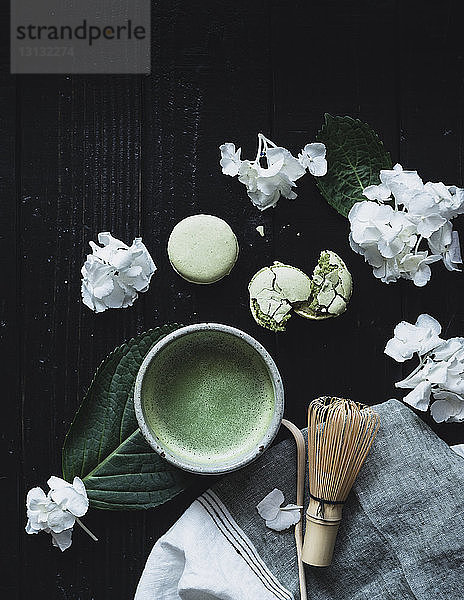 Draufsicht auf Matcha-Tee mit Makronen und Hortensien auf dem Tisch