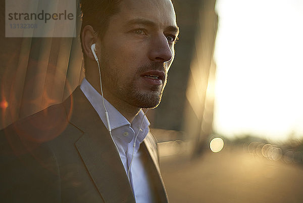 Selbstbewusster Geschäftsmann  der Musik hört  während er im Freien steht