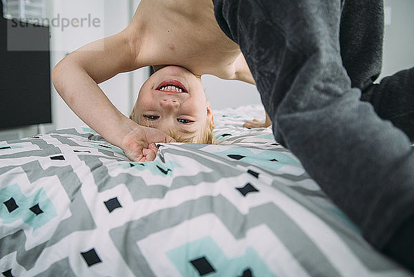 Porträt eines verspielten Jungen im Bett zu Hause