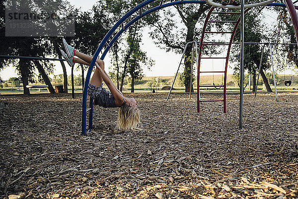 Seitenansicht eines glücklichen Mädchens  das auf Affenstangen auf dem Spielplatz spielt