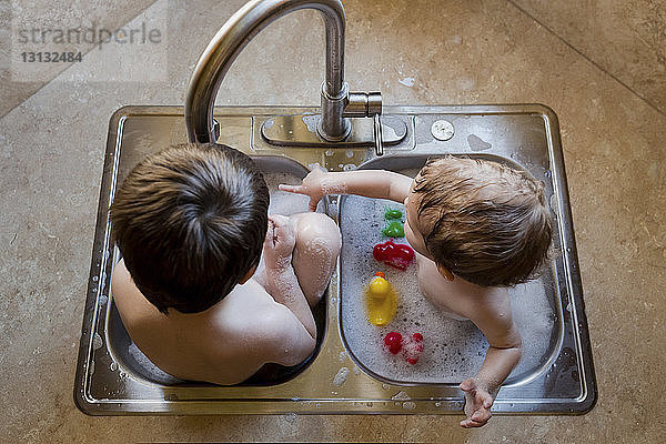 Hochwinkelaufnahme von Brüdern  die mit Wasser im Waschbecken spielen