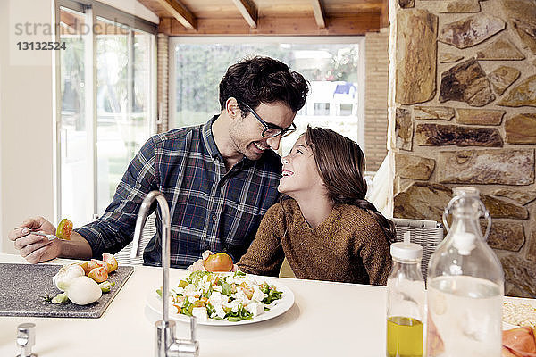 Glückliche Vater und Tochter essen Salat  während sie am Tisch sitzen