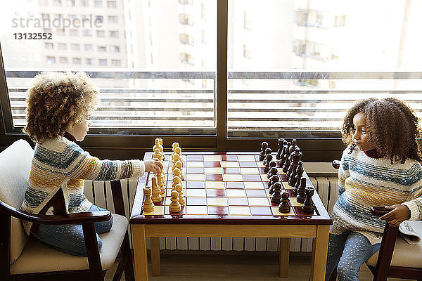 Schwestern spielen zu Hause am Tisch Schach