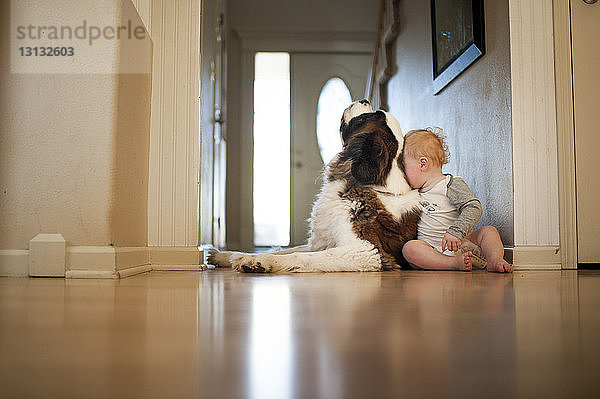 Säugling in voller Länge mit Hund zu Hause sitzend