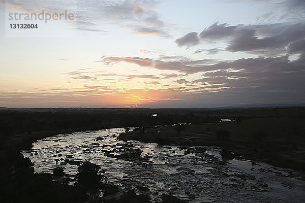 Panoramablick auf den Fluss inmitten der Landschaft im Serengeti-Nationalpark bei Sonnenuntergang