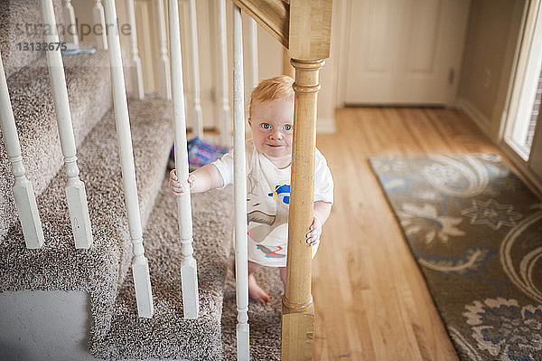 Hochwinkelporträt eines süßen kleinen Jungen  der zu Hause auf Stufen steht