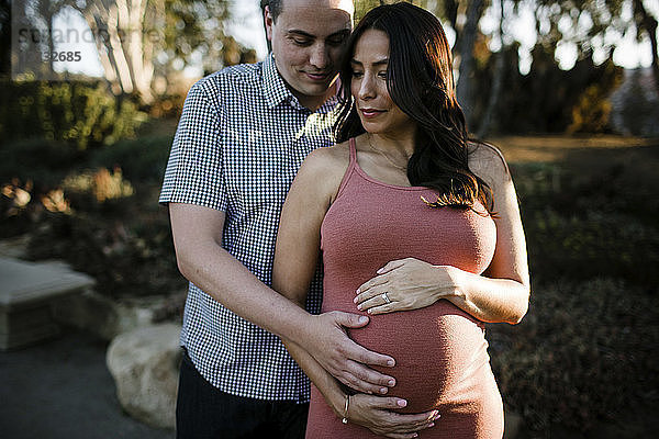 Ehemann berührt den Bauch der schwangeren Frau  während er im Park steht