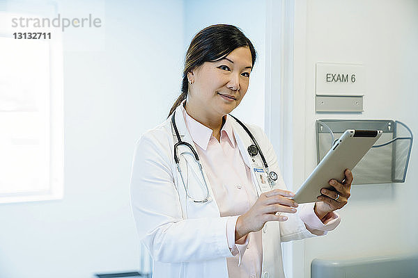 Porträt einer Ärztin  die einen Tablet-Computer im Krankenhauskorridor hält