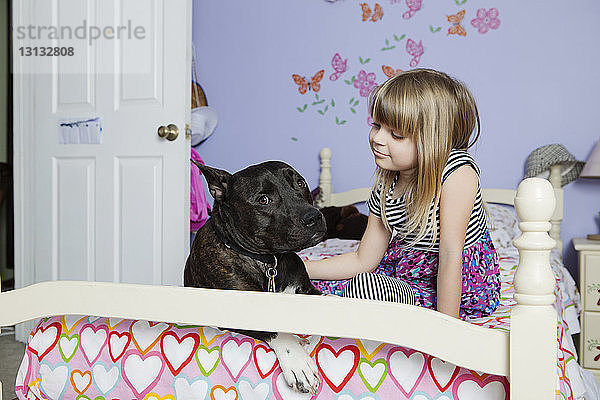 Süßes Mädchen mit Hund auf dem Bett zu Hause