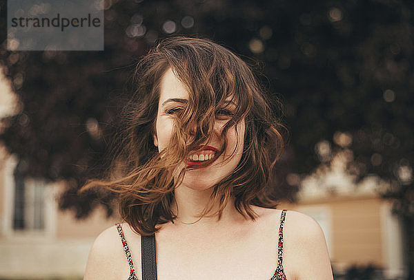 Porträt einer glücklichen jungen Frau mit zerzaustem Haar im Freien