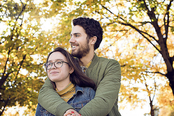 Nachdenkliches junges Paar umarmt sich im Herbst im Park