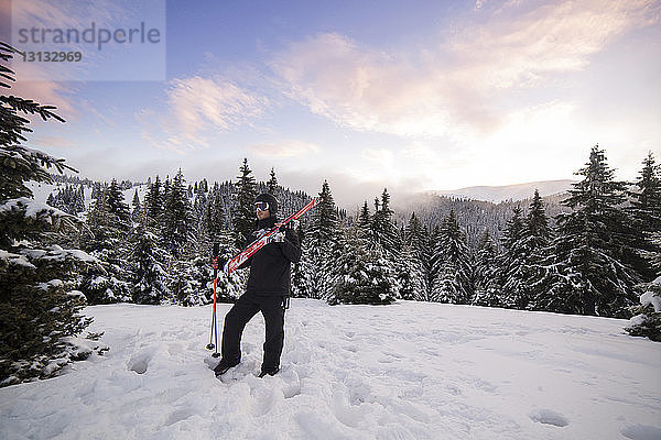 Skifahrer steht auf verschneitem Berg gegen den Himmel