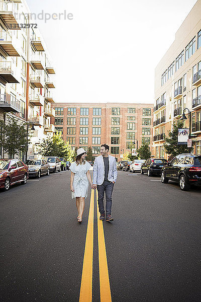 Glückliches Paar geht an einem sonnigen Tag auf der Straße inmitten von Gebäuden