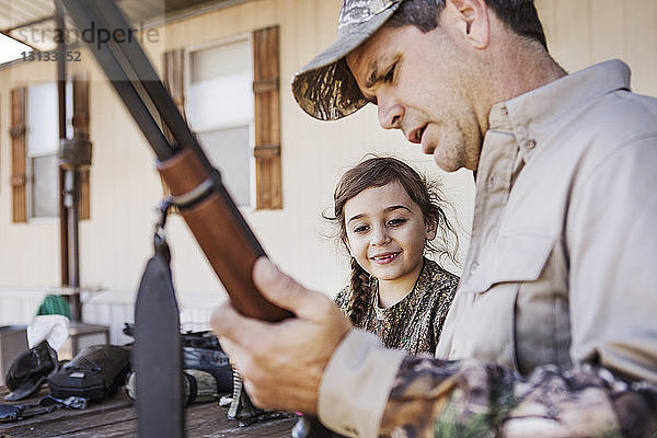 Mädchen beobachtet Vater mit Gewehr in der Hand