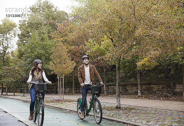 Glückliches Paar beim Fahrradfahren auf der Straße im Park