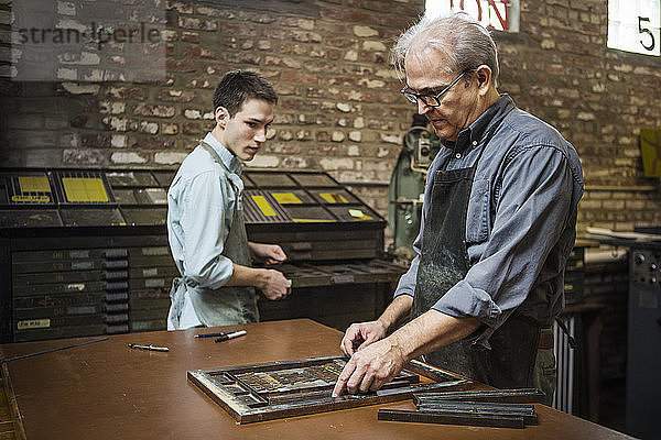 Arbeiter ordnet Buchdruckausrüstung auf der Werkbank in der Werkstatt an
