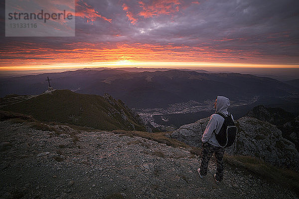 Mann steht bei Sonnenuntergang auf Berg