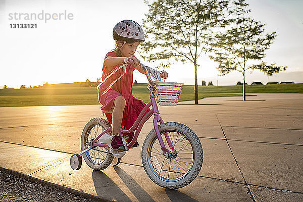 Zuversichtliches Mädchen lernt Fahrradfahren gegen den klaren Himmel im Park