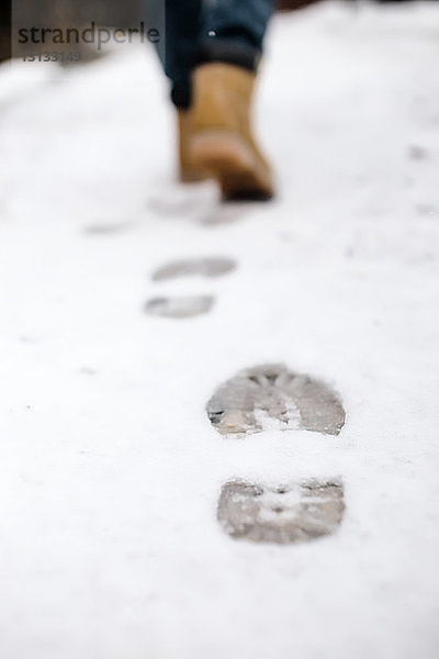 Niedriger Teil der Frau hinterlässt Fussspuren auf schneebedecktem Fussweg