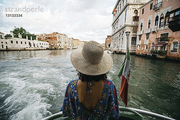 Rückansicht einer Frau  die im Boot über den Kanal in der Stadt fährt