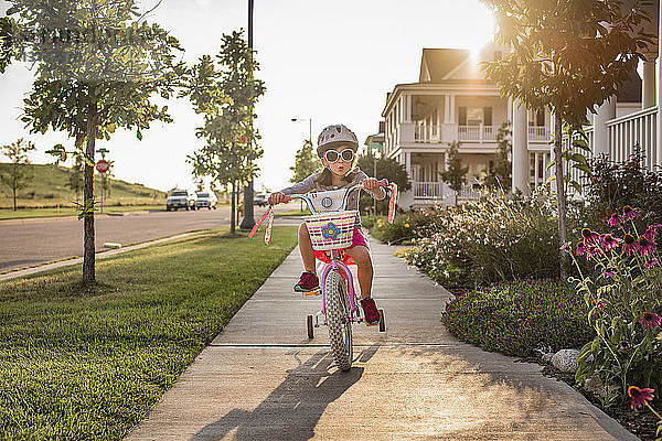 Verspieltes Mädchen mit Sonnenbrille beim Fahrradfahren