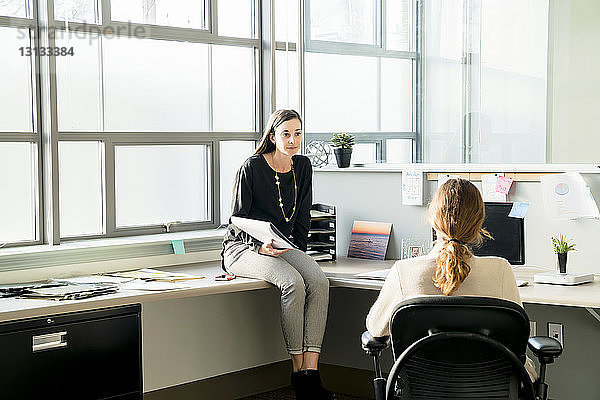 Geschäftsfrauen  die im Büro sitzen und reden