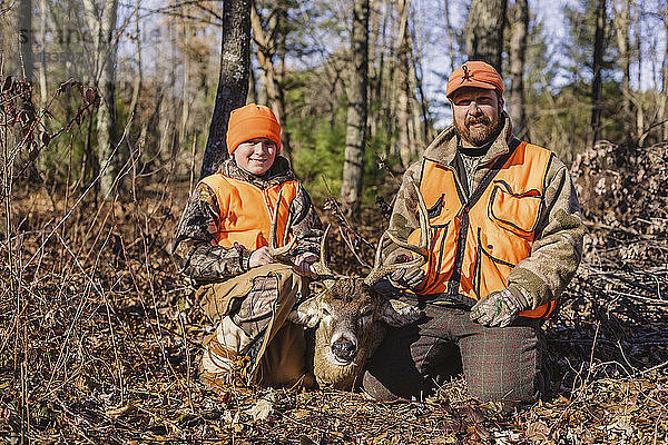 Porträt von Vater und Tochter mit toten Hirschen auf dem Feld bei der Jagd