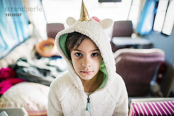 Hochwinkelporträt eines Mädchens in Kapuzenhemd mit Partyhut zu Hause