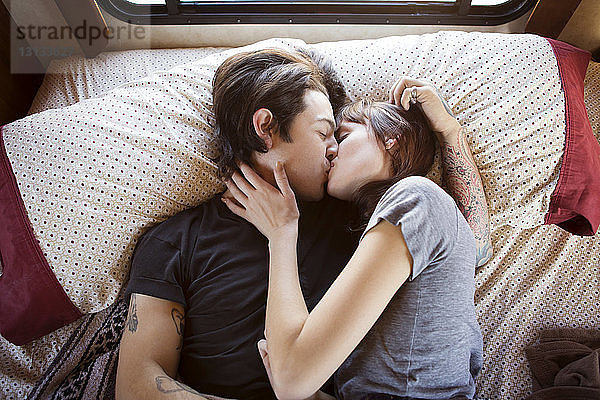 Paar küsst sich im Bett liegend im Wohnmobil