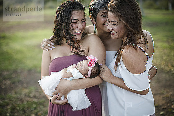 Glückliche Familie mit neugeborenem Mädchen im Park stehend