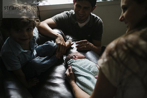 Glückliche Familie mit neugeborenem Jungen zu Hause