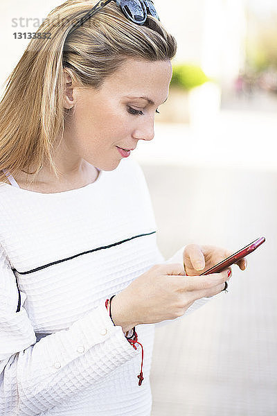 Frau benutzt Mobiltelefon  während sie auf einem Fußweg steht