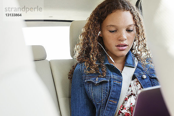 Niedriger Blickwinkel eines Teenagers  der im Auto sitzt und Musik hört