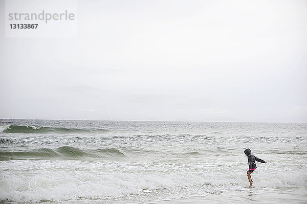 Seitenansicht eines Mädchens  das im Meer gegen den klaren Himmel spielt