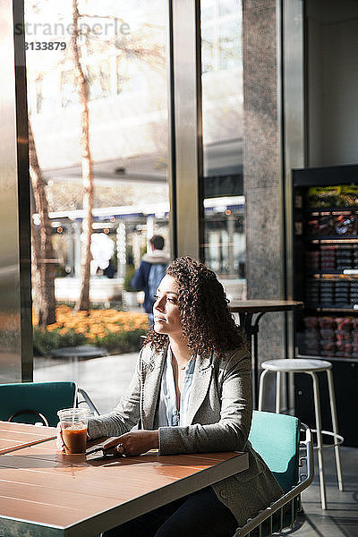 Nachdenkliche Geschäftsfrau sitzt am Café-Tisch