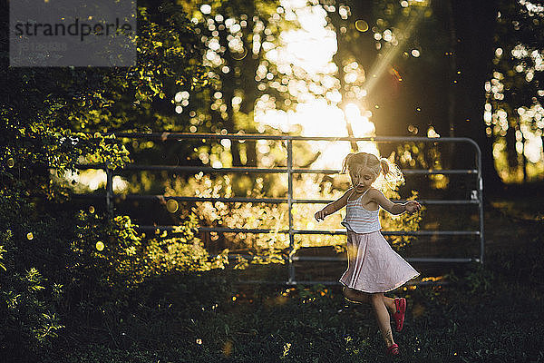 Fröhliches Mädchen tanzt auf Grasfeld im Hinterhof