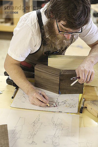 Hochwinkelansicht einer Zeichnungsskizze eines Zimmermanns im Stehen an der Werkbank