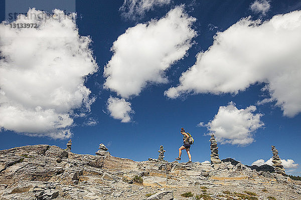 Niedrigwinkelaufnahme einer Wanderin  die auf Felsformationen vor bewölktem Himmel im North Cascades National Park wandert