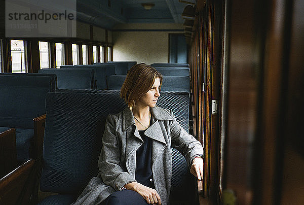 Nachdenkliche Frau  die durch das Fenster schaut  während sie im Zug sitzt