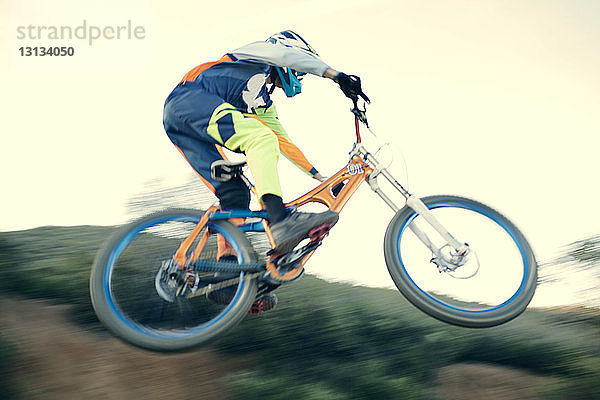 Niedrigwinkelansicht eines Mountainbikers  der bei klarem Himmel einen Stunt macht