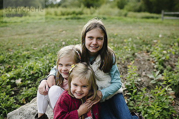 Porträt von fröhlichen Schwestern auf dem Feld im Park