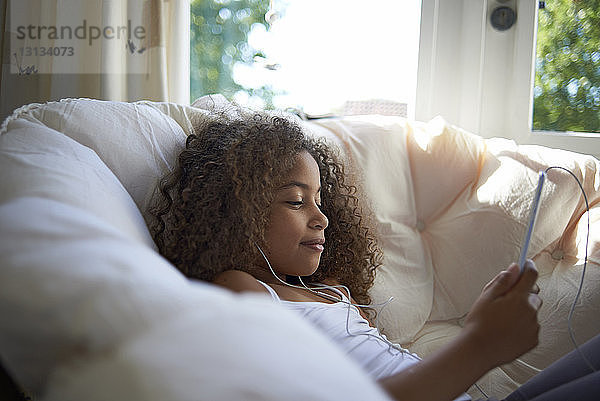 Mädchen benutzt einen Tablet-Computer  während sie zu Hause Musik hört