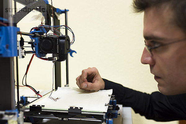 Zuversichtlicher Ingenieur untersucht 3D-Drucker auf dem Tisch