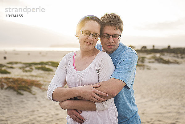 Mann umarmt Frau  während er am Strand steht