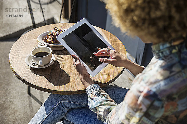 Hochwinkelansicht einer Frau  die ein digitales Tablett benutzt  während sie im Straßencafé sitzt